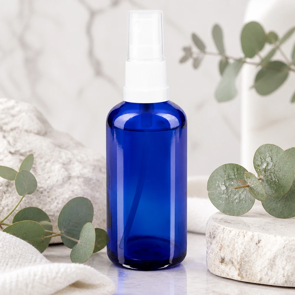 Flacone spray blu da 50ml STD bianco/trasparente apoGlas Flacone spray in vetro blu da 50 ml con nebulizzatore bianco su fondo marmorizzato con motivo eucalipto