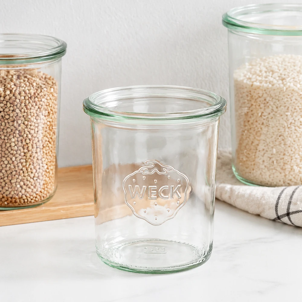 WECK 160ml RR60 mason jar con bordo verde e logo, mason jar vuoto accanto a barattoli pieni su tavola di legno