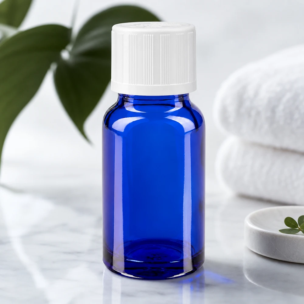 Contagocce blu da 10ml. STD KiSi bianco/1,2mm ApoGlas Vaso da farmacia blu da 10 ml con tappo di sicurezza per bambini bianco, posato su una superficie di marmo accanto ad asciugamani piegati