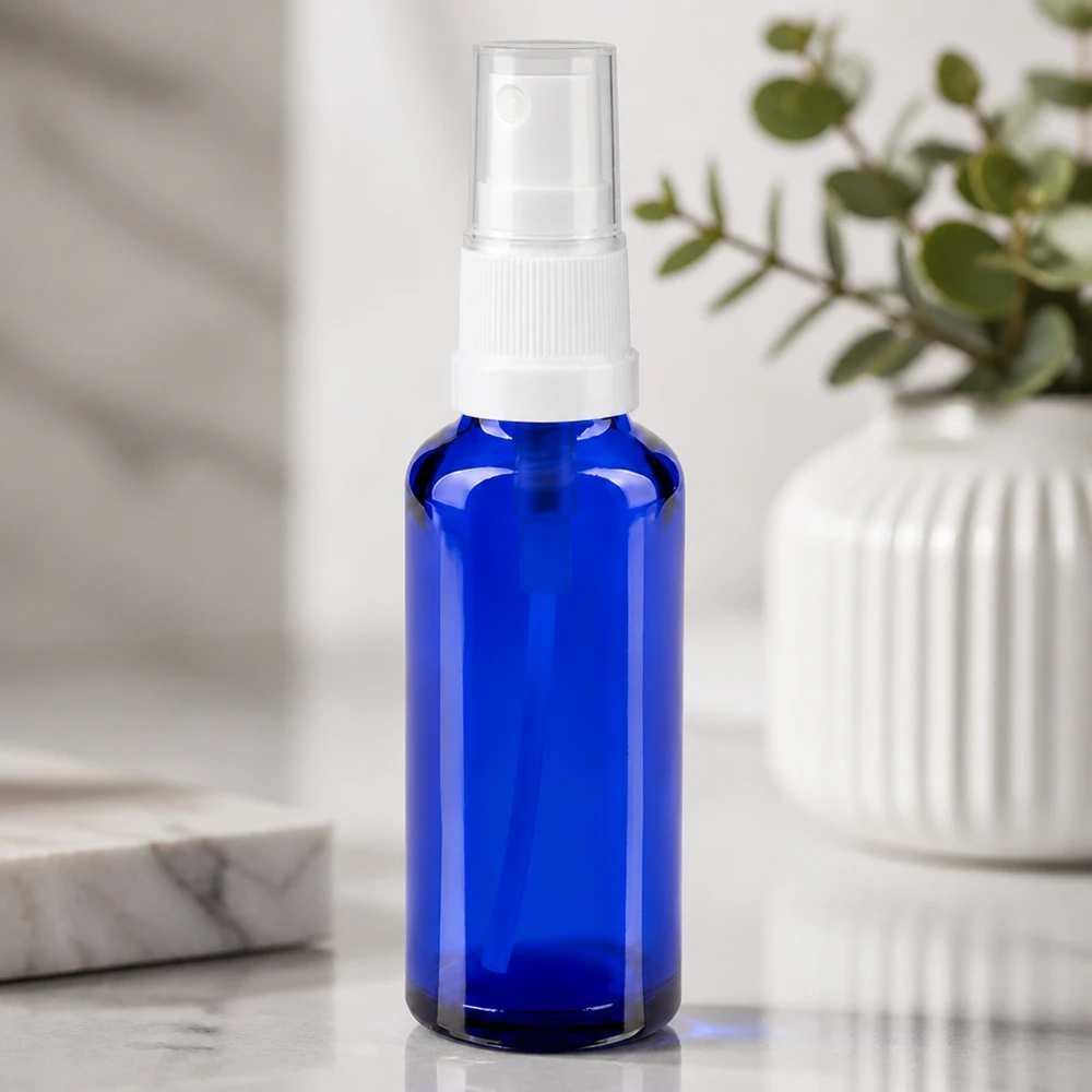 Flacone di vetro da farmacia blu da 30 ml con erogatore a spruzzo bianco su sfondo di marmo bianco