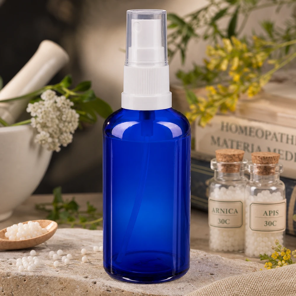 Flacone spray blu da 50ml STD bianco/trasparente apoGlas Flacone spray in vetro da farmacia blu da 50 ml con erogatore bianco, accanto a globuli omeopatici