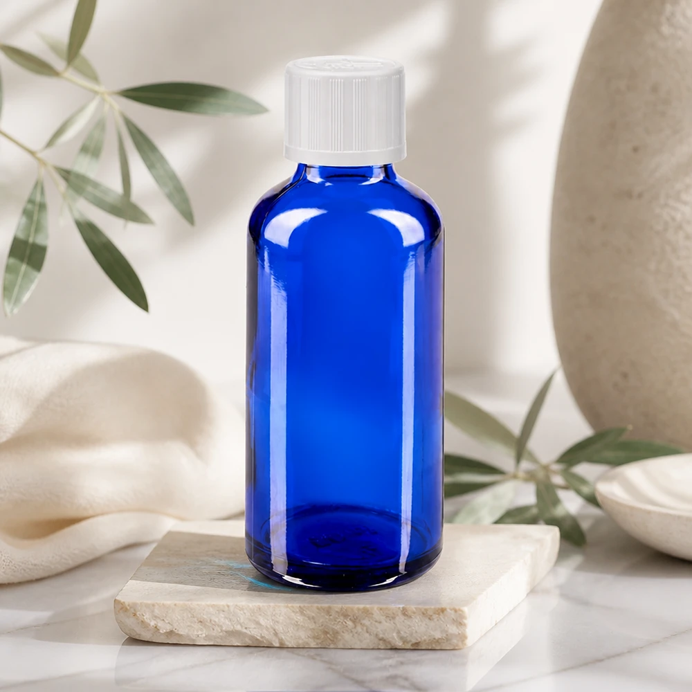 Contagocce blu da 50 ml. STD KiSi bianco/1,2mm ApoGlas Bottiglia di vetro blu da 50 ml con tappo a vite bianco su una lastra di marmo in un ambiente naturale e luminoso